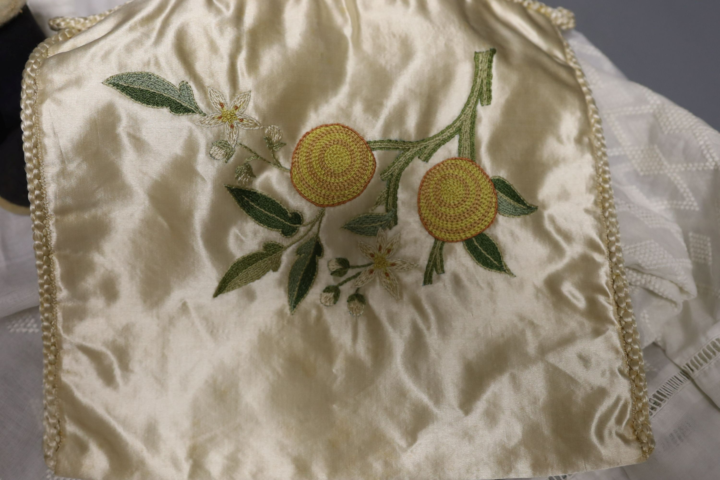 A pair of felt fur-lined child's boots and a whitework communion dress, a handkerchief sachet and two satin embroidered sachets